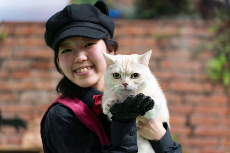 ショーに出る白いネコを抱えて笑顔の飼育員の橋本さんの写真
